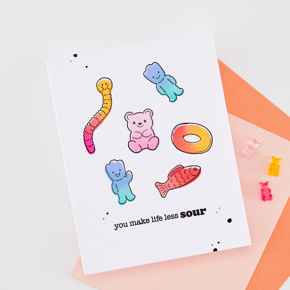 Colorful gummy bear stickers on a white card with text, placed on a light background.