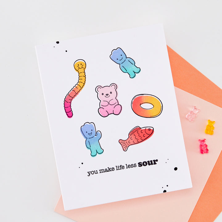 Colorful gummy bear stickers on a white card with text, placed on a light background.